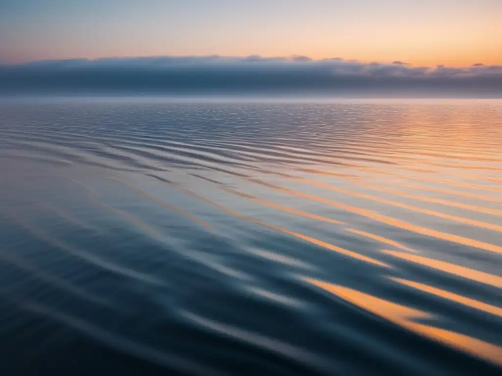 Imagen marítima en blanco y negro de un sereno amanecer en el océano, reflejando el sol en el horizonte