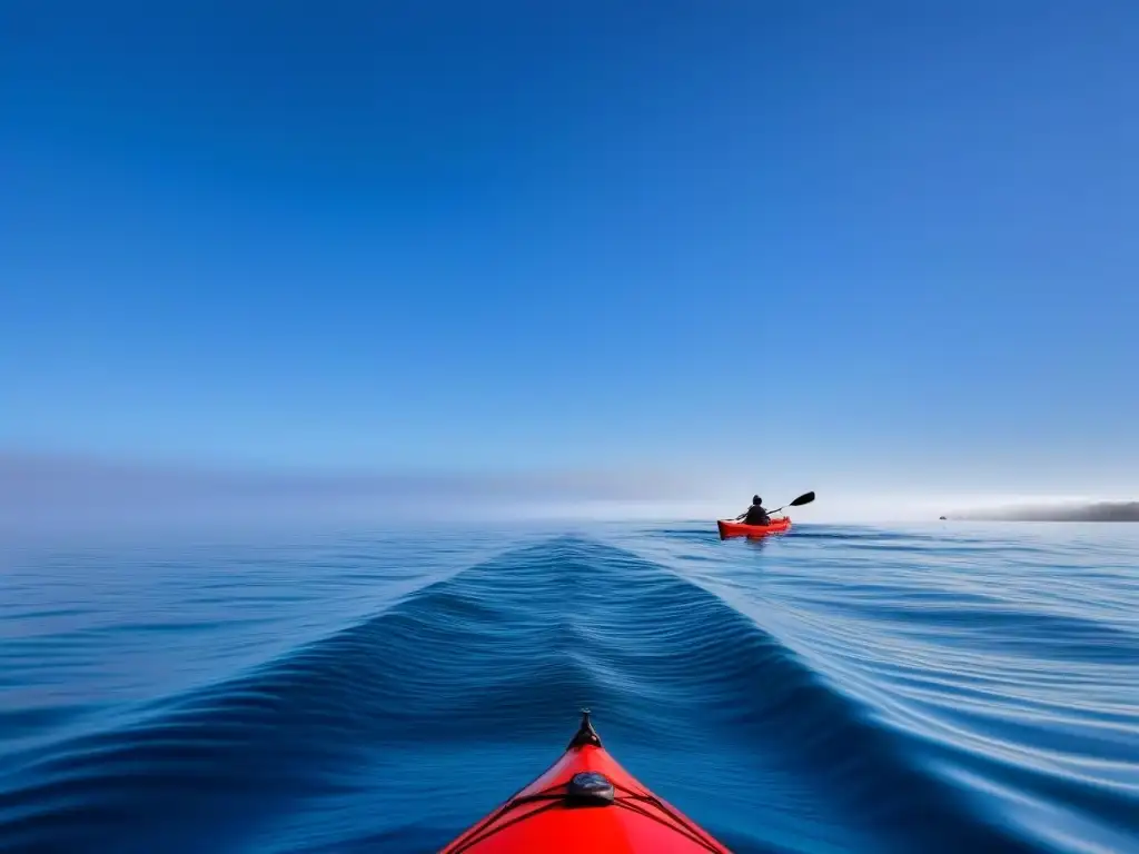 Un kayak rojo surcando sereno las aguas, reflejando el cielo azul